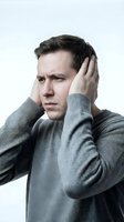 Stressed Caucasian man in gray sweater holding head with both hands expressing headache pain and mental pressure isolated on white background.