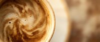 Creamy cappuccino with latte art swirl in white cup, close-up of hot beverage with foam and espresso design for café and coffee shop use.