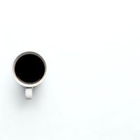 White coffee cup with black coffee viewed from above on clean white background with copy space for text and design projects.