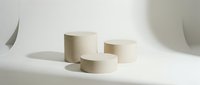 Three minimalist beige cylinder podiums arranged on a white surface with soft shadows, perfect for product display and cosmetic presentation.