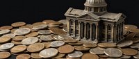 Miniature government building model surrounded by scattered coins representing financial concepts, budget planning, taxation, and economic policy decisions.