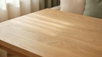 Natural wood grain table surface with warm lighting in modern interior setting for furniture and home decor applications.