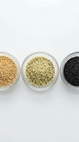 Three glass bowls containing different seeds and grains arranged in row on white background for healthy cooking and nutrition concepts.