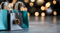 Festive shopping bags in turquoise and silver with pine cone decoration against blurred golden bokeh lights background, holiday retail and gift concept.