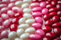 Colorful pharmaceutical capsules and pills in red, pink and white colors scattered together creating medical healthcare background for pharmacy concepts.