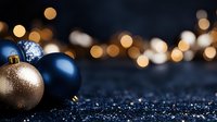 Navy blue and gold Christmas baubles on dark glittery surface with blurred golden bokeh lights creating festive holiday atmosphere for seasonal decorations.
