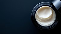 Luxury white face cream in black jar on dark background, top view close-up. Minimalist cosmetic product photography for beauty and skincare marketing.