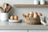 Fresh brown eggs in woven basket on light kitchen counter with wooden utensils and minimalist decor, natural light creates soft shadows for rustic farmhouse feel.