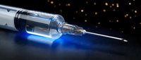Medical syringe with blue glowing liquid on dark surface with bokeh lights background for healthcare and pharmaceutical concepts.