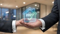 Businessman in dark suit holding glowing holographic house icon with 2027 year and checkmark symbol, representing future real estate investment, property purchase, home ownership goals, and digital technology in modern office environment.