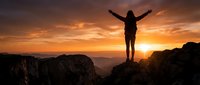 Woman hiker celebrating success on mountain peak at golden sunrise with arms raised, dramatic sky and valley landscape below for adventure travel concepts.