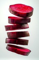 Fresh beetroot slices falling in dynamic stack showing vibrant red purple interior and natural skin texture isolated on white background for healthy cooking.