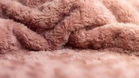 Soft pink fluffy fabric texture with cozy plush material surface for home decor and textile design projects.