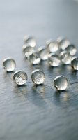 Clear glass marbles scattered on wooden surface with soft natural lighting creating elegant reflections and shadows for luxury design projects.