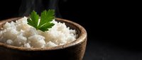 Steamed white rice in wooden bowl garnished with fresh parsley on dark background. Healthy grain side dish for Asian cuisine and comfort food meals.