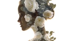 Young woman silhouette profile with white roses and eucalyptus leaves creating artistic double exposure effect for beauty and wellness concepts.