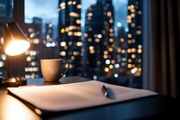 Cozy evening workspace with coffee cup and desk lamp against blurred city lights backdrop, creating atmospheric home office ambiance for remote work setting.