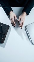 Professional businesswoman hands with black nail polish gesturing over white desk with laptop and smartphone for corporate presentation concepts.