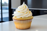 Vanilla cupcake with swirled buttercream frosting on white surface against dark background, fresh homemade dessert with creamy topping for bakery or cafe menu.