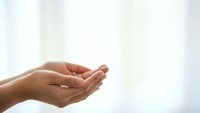 Open cupped hands in prayer or receiving gesture against soft white background symbolizing hope, faith, spirituality and divine connection.