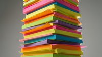 Colorful stacked papers in rainbow hues arranged in a tower formation against neutral background, representing creativity, organization, and design concepts.