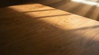 Warm sunlight streaming across polished wooden floor surface creating natural shadows and highlighting rich grain texture for interior design projects.