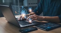 Business professional using laptop with holographic digital interface displaying data analytics and futuristic technology elements for modern workspace.
