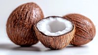 Fresh coconuts on white background, one cut in half showing white flesh inside. Natural tropical fruit composition with selective focus and soft lighting.