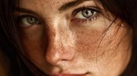 Close-up portrait of young Caucasian woman with intense green eyes, natural freckles, and dark hair falling across face in dramatic lighting.