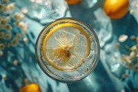 Refreshing glass of sparkling water with lemon slice from above, ice cubes and citrus fruits on turquoise background, perfect for summer drink menu or healthy lifestyle concept.