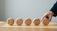 Business hand selecting happy face wooden block from sad to positive emotions representing customer satisfaction and feedback concept.