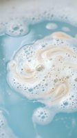 Creamy foam swirls in turquoise water creating abstract patterns with bubbles for spa wellness skincare cosmetic product backgrounds and relaxation concepts.