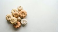 Miniature decorative pumpkins in neutral autumn colors arranged on white background for seasonal crafts and fall holiday decorations.