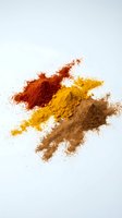 Colorful spice powder mix with turmeric, paprika and cinnamon scattered on white background for culinary and cooking projects.