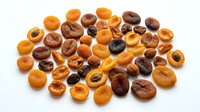 Dried apricots and prunes scattered on white background, ready for food packaging, recipe blogs, nutrition content, and culinary design projects.