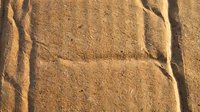 Footprint impression in golden sand texture with natural shadows and warm lighting for travel and adventure concepts.