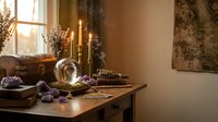 Cozy autumn dining room interior with wooden table, lit candles, purple flowers, vintage decor and warm natural lighting for seasonal home design.