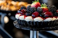 Gourmet cupcake topped with fresh berries, whipped cream frosting, and blackberries on elegant cake stand. Perfect for bakery, dessert, and food photography needs.