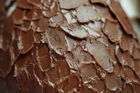 Rich chocolate frosting texture with rough, layered surface creates appetizing close-up pattern. Creamy brown icing shows detailed peaks and swirls for dessert photography.