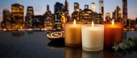 Romantic candles glowing at twilight with city skyline backdrop. Spa relaxation, meditation, aromatherapy concept for wellness and self-care lifestyle.