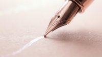 Fountain pen with rose gold nib writing on textured paper, suitable for stationery, writing, calligraphy, and creative design projects.