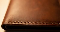 Brown leather material with detailed stitching showcasing craftsmanship and texture for luxury goods, fashion accessories, and artisan products.