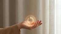 Glowing clock floating above open palm against soft curtain backdrop, symbolizing time management, productivity, and business concepts for corporate design projects.