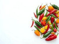 Colorful hot chili peppers in red, yellow, and green varieties arranged on white background for food, cooking, and culinary design projects.