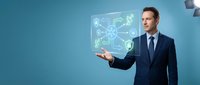 Professional businessman in navy suit presenting holographic digital network interface with connected icons on blue background for technology presentations.