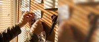 Craftsman adjusting wooden window blinds with natural sunlight streaming through, showcasing carpentry and home improvement work.