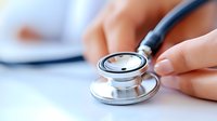 Medical professional holding stethoscope during patient examination, closeup view of healthcare provider hands on white desk with documents in background.