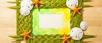 Tropical summer frame made from woven palm leaves with starfish and sand dollars on wooden background for vacation memories and beach themes.