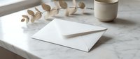 White envelope on marble surface with eucalyptus branch and ceramic cup creating elegant minimalist stationery mockup for branding and correspondence.