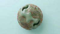 Carved jade sphere with intricate relief patterns featuring birds and foliage, isolated on light background, suitable for luxury design, home decor, and editorial use.